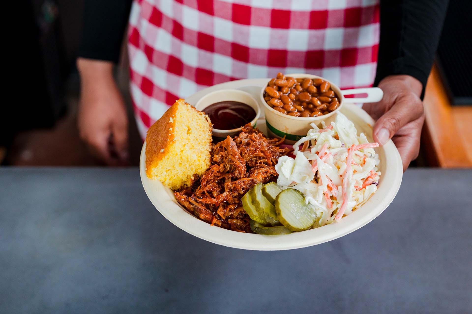 A server holds a delicious meal piled on a compostable plate